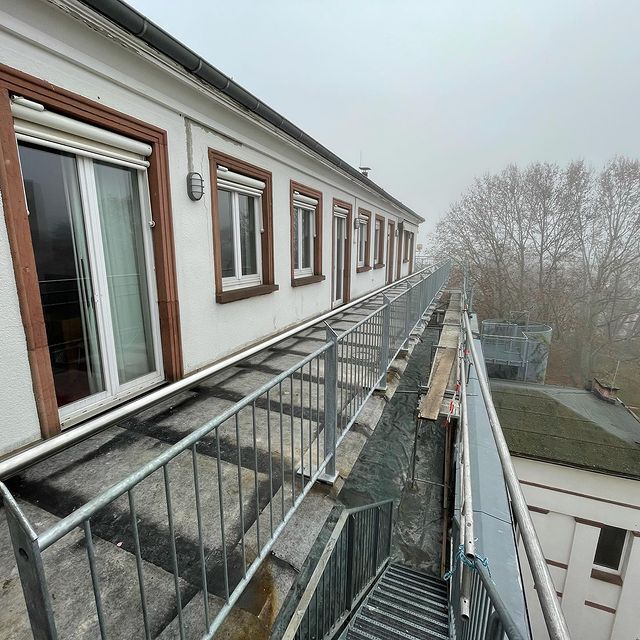 Balkongeländer mit Glasfüllung und Edelstahl-Handlauf an einem Laubengang