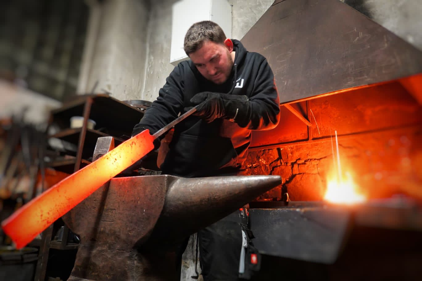 Metallbaumeister schmiedet glühenden Stahl am Amboss