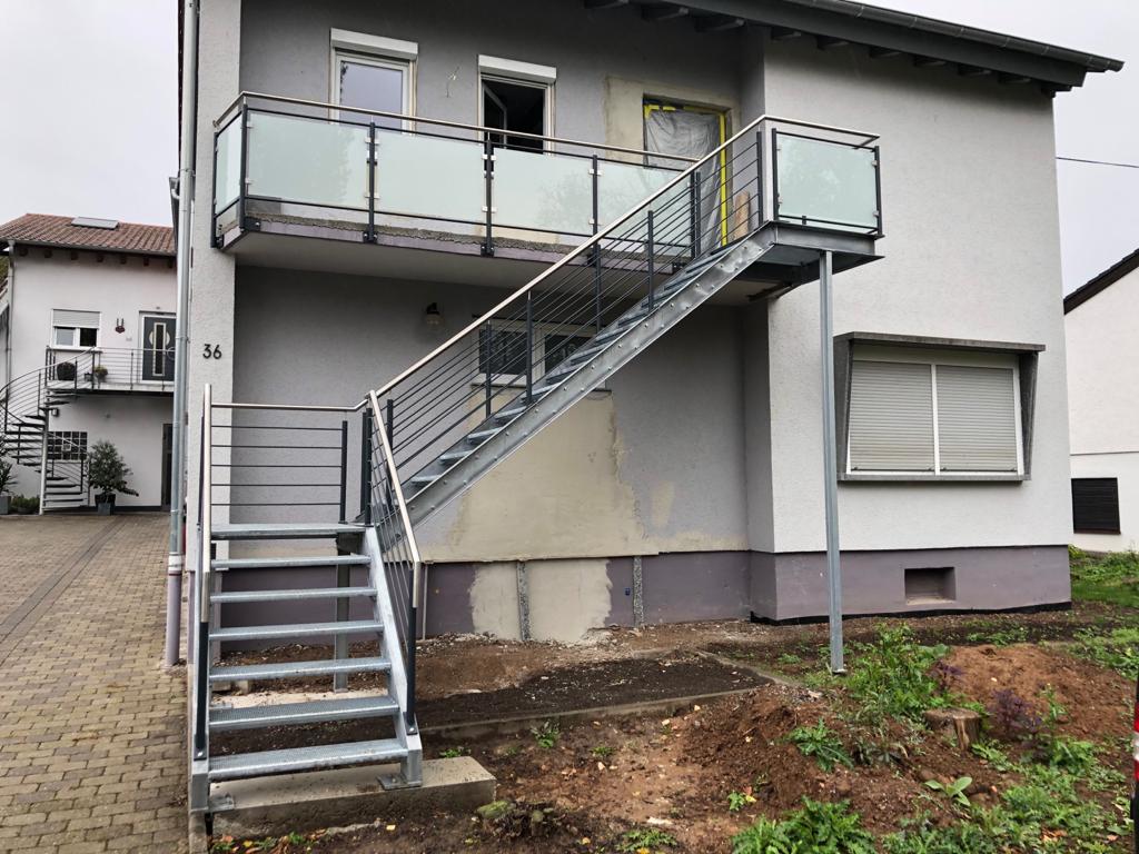 Verzinkte Außentreppe mit Podest und Balkongeländer an einem Wohnhaus