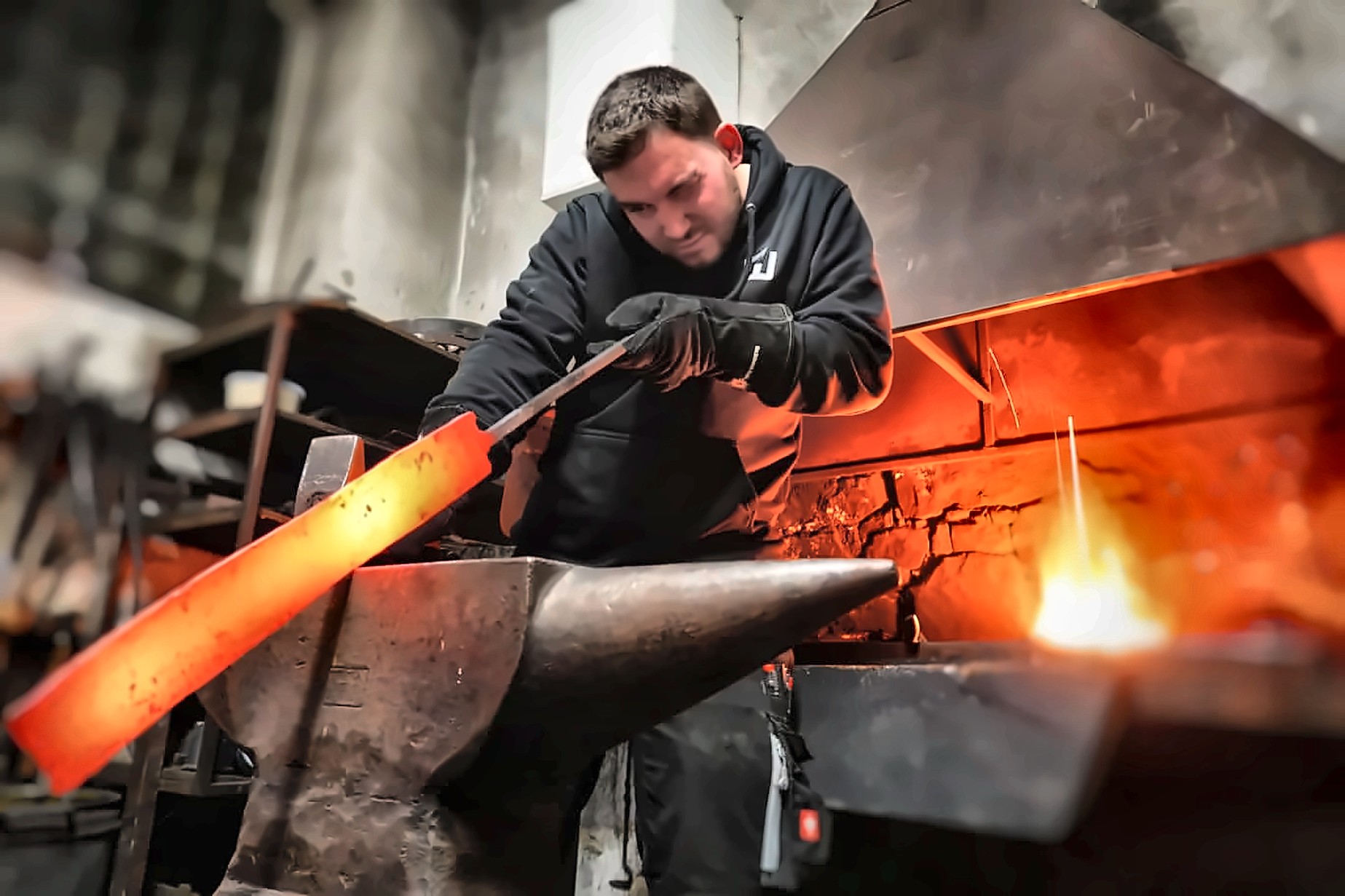Metallbaumeister schmiedet glühenden Stahl am Amboss